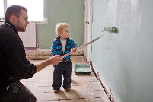 Father and son paint wall together